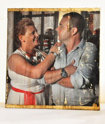 A printed photograph showing two adults standing indoors, facing each other and smiling, with visible wear and texture on the photo surface.