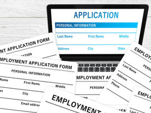 computer with job application on the screen surrounded by paper applications