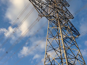Power pole and lines against a blue sky and clouds.