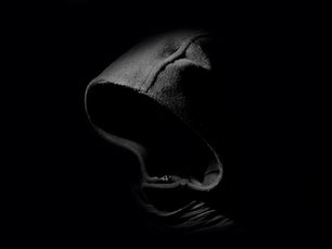 A dark hoodie on a black background, evoking anonymity.