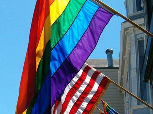 Rainbow flag and american flag hanging from building
