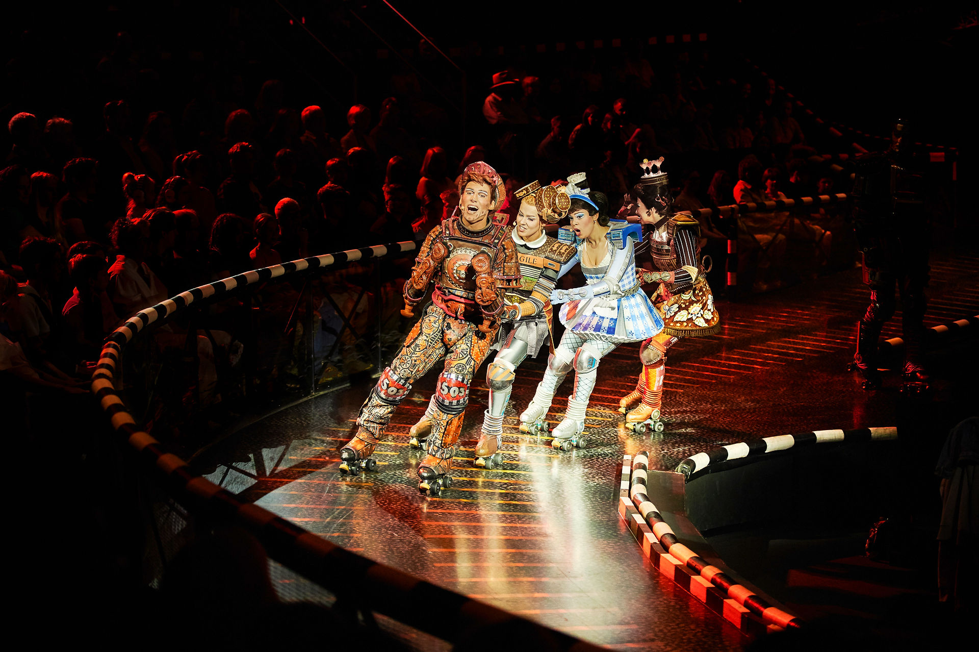 Four Starlight Express characters performing on roller skates along the curved arena track, dynamically illuminated by moving lights controlled through the zactrack PRO real-time tracking system.
