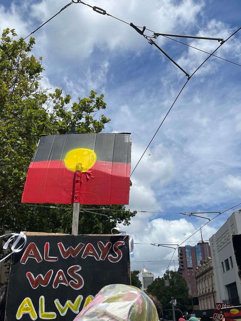 Image of a handpainted Aboriginal flag, and a sign that says "always was, always will be" with blue sky and a tree in the background.