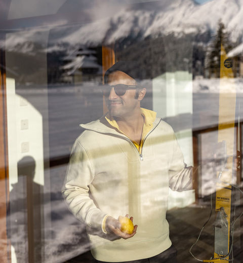 Man looking through window with skis in his hands.