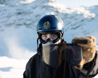 Man with ski helmet holding his goggle lens.