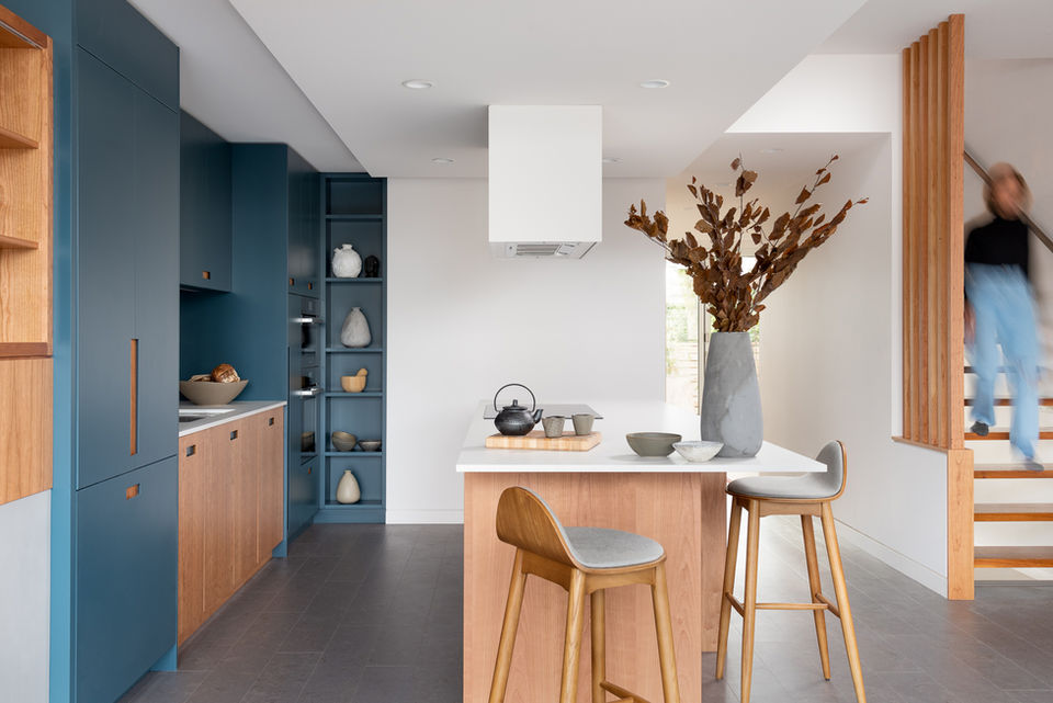 Featured in western living, a custom designed kitchen with cherry wood and teal back bar. Fan hood over the kitchen island. Extra display for cookbooks. Cork flooring and wood slat opening in staircase.