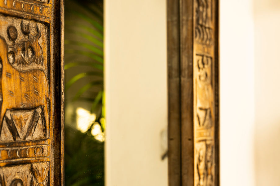 Close-up of carved wooden panel with intricate patterns, softly lit with a blurred background highlighting texture and craftsmanship