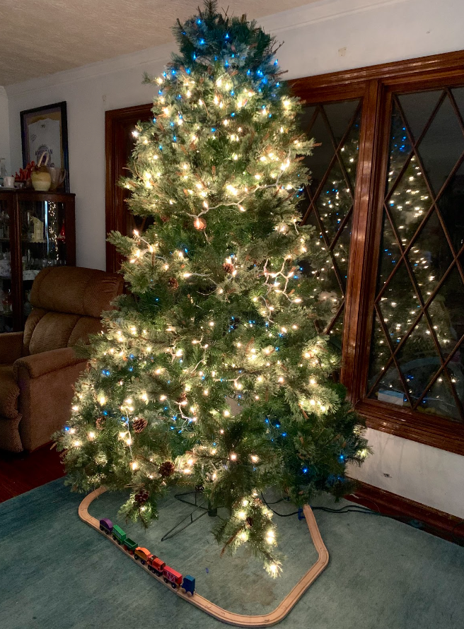 An artificial Christmas tree is being displayed in front of a window in a living room. Photo by Madison Bibbey.