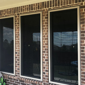 three windows with dark colored security screen mesh covers