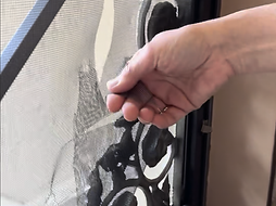 A girl's hand pulling on a torn security storm door screen
