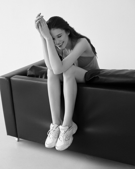 Personal portrait of Karina seated on a couch with her head down, photographed by Alexandr Mukhin
