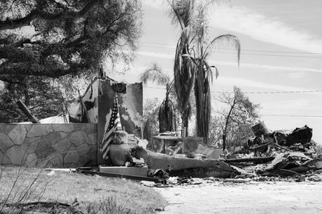 Burned home with American flag after fire disaster. Overturned furniture and debris.