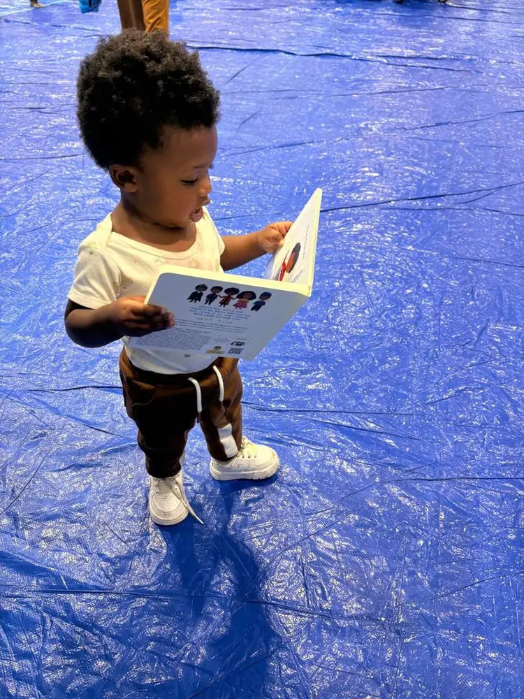 A toddler reading a new book at a community event