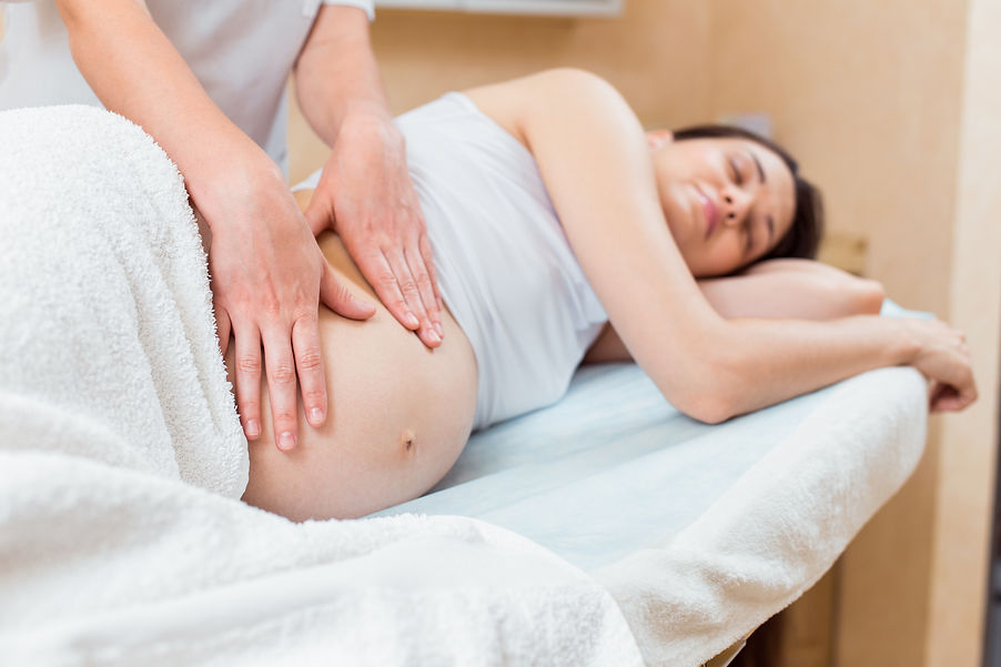 beautiful-pregnant-brunette-with-long-hair-lies-her-side-reception-with-massage-therapist-