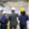 ingeniero-masculino-empleadas-fabrica-cascos-caminando-sobre-piso-planta-hablando-hombre-a