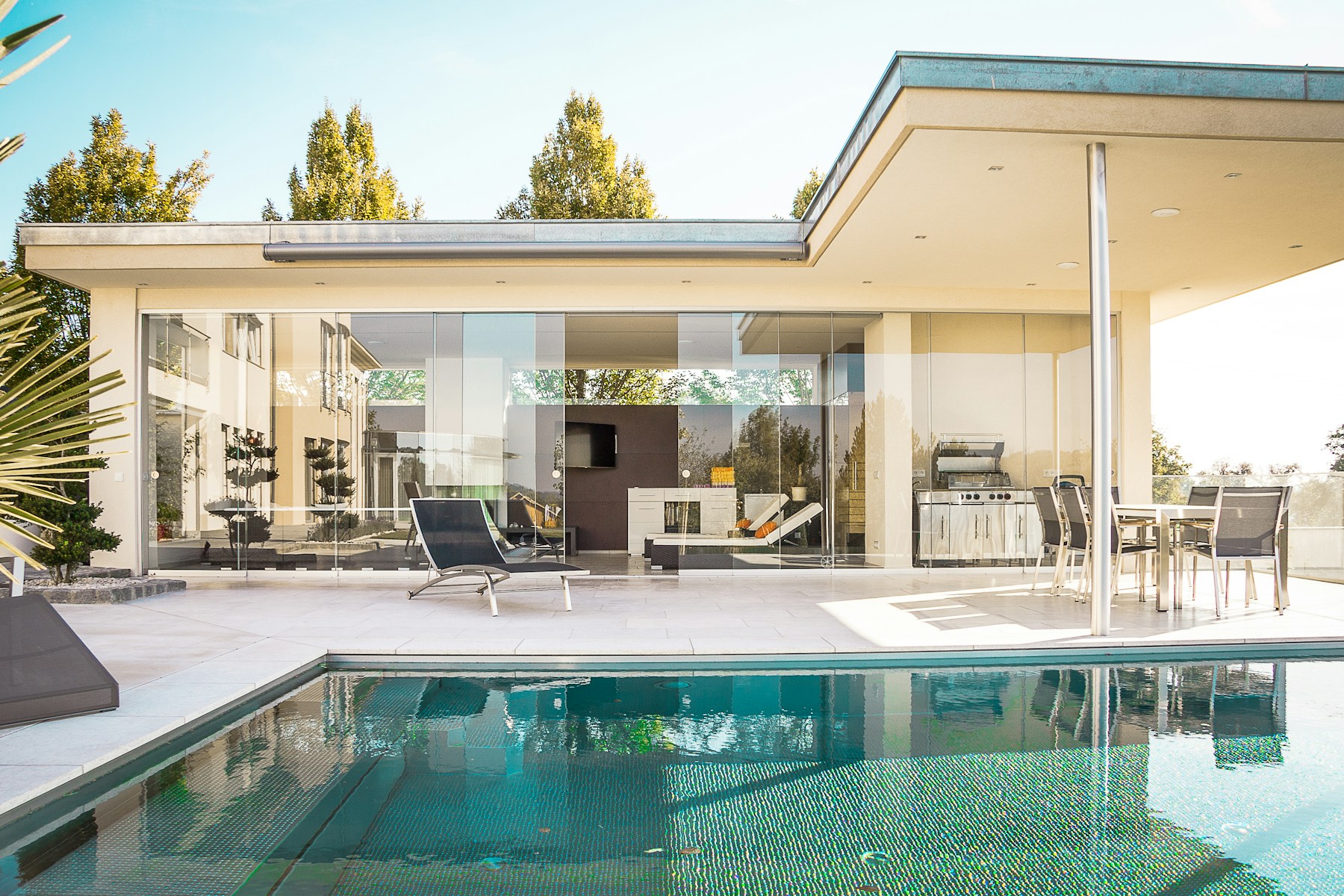 Glass-walled rental house with a pool and lounge chairs