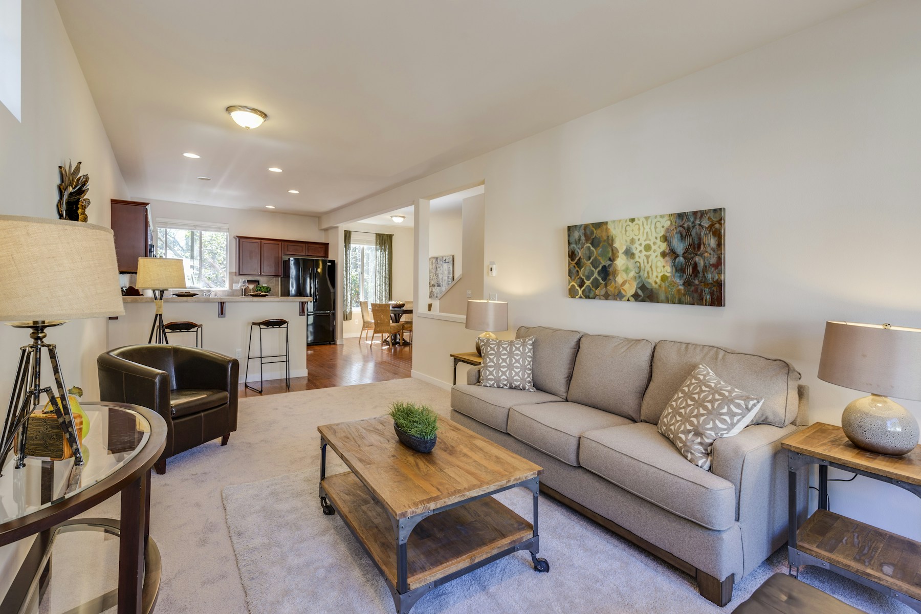 Open rental living room with a gray sofa and kitchen beyond