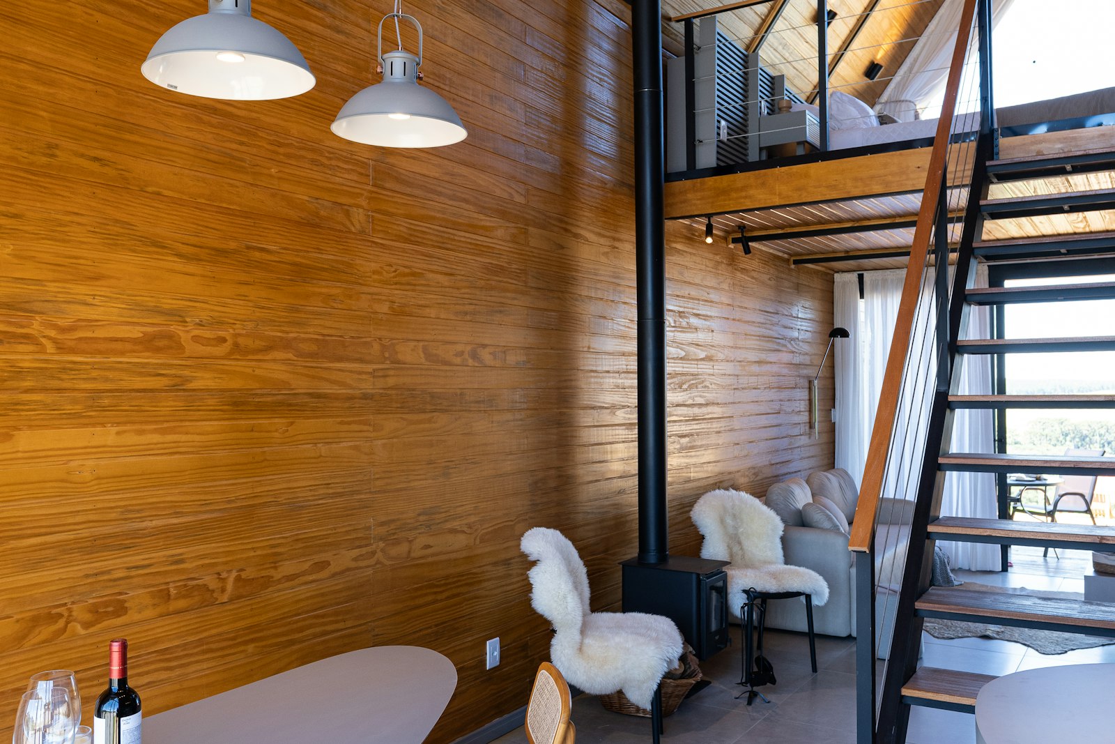 Wood-paneled short-term rental loft with a loft bed and wood stove