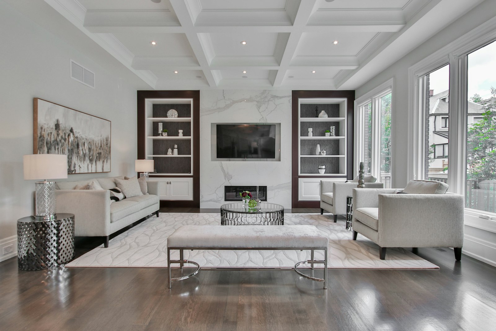 Formal living room with coffered ceiling, marble fireplace, and paired chairs