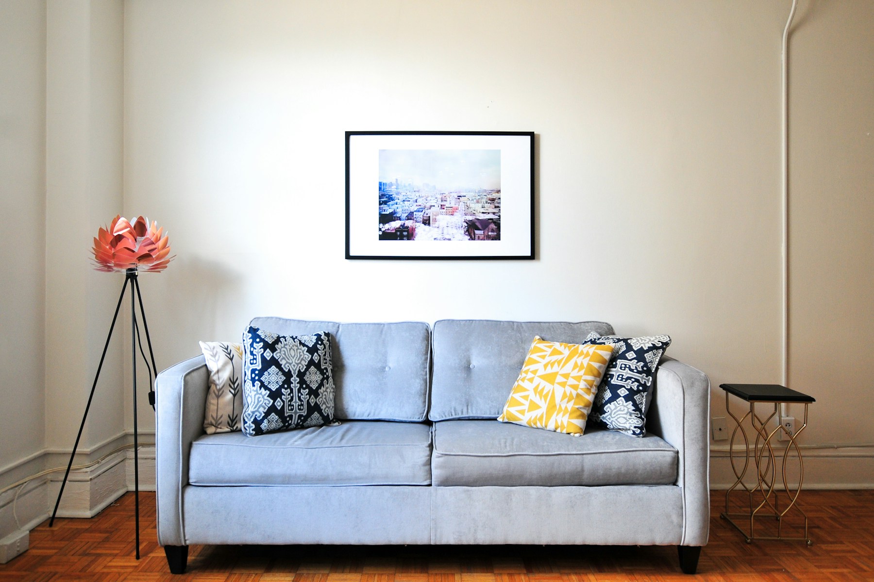Light-blue sofa with patterned pillows and a lotus floor lamp