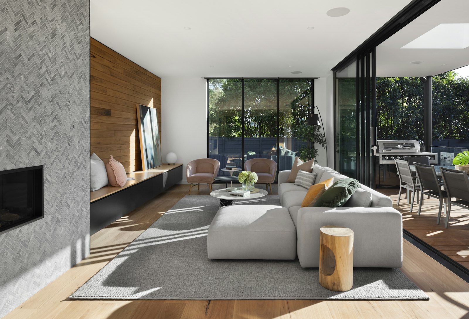 Open living room with a light sectional, herringbone fireplace, and patio doors