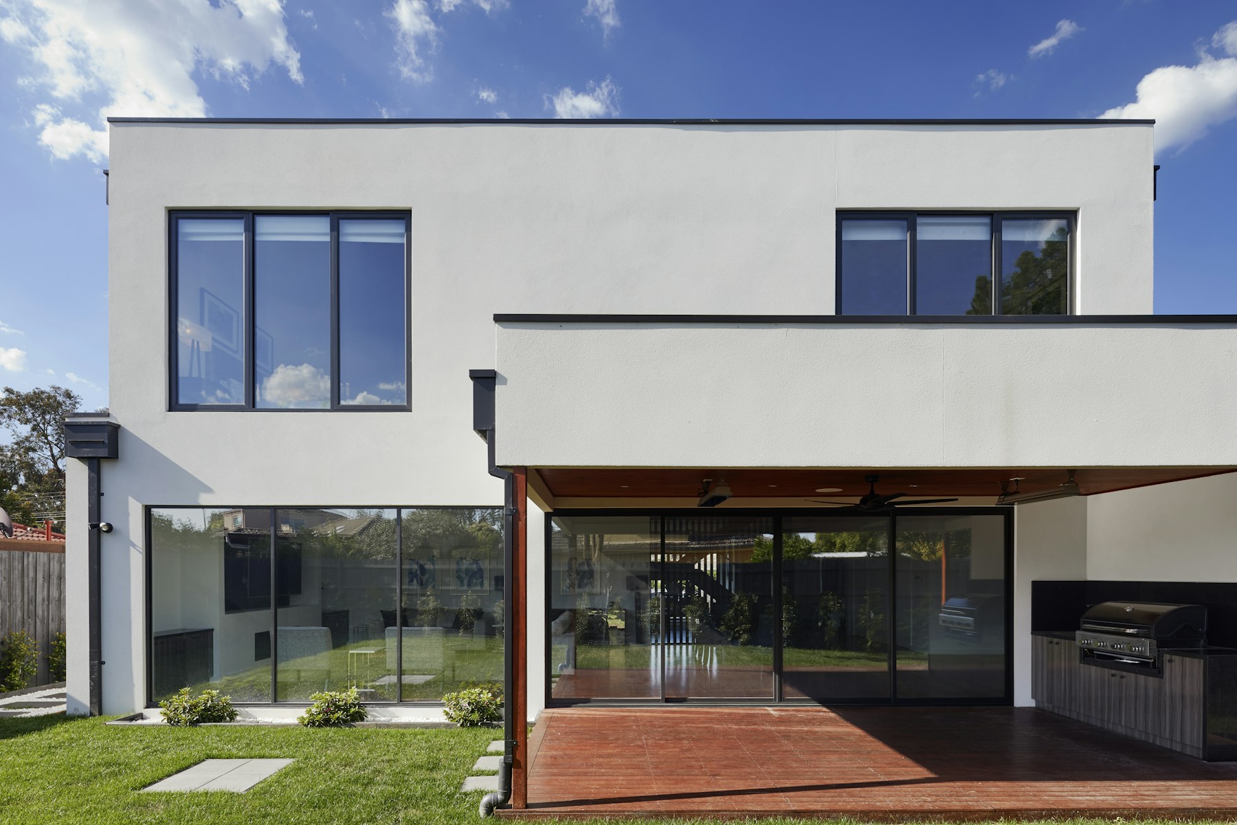 Modern white rental with a covered patio and grill