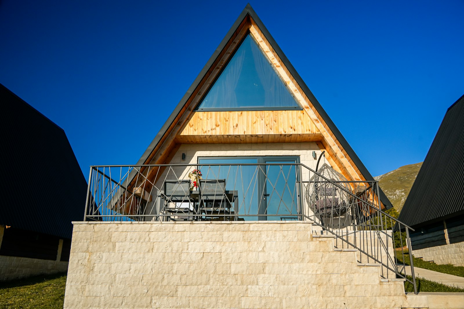 A-frame short-term rental with a stone terrace and balcony