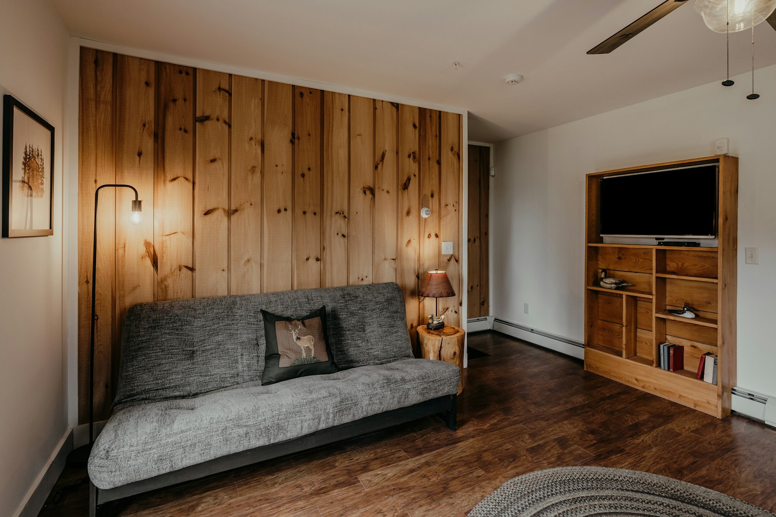 Cabin rental den with a futon, pine wall, and TV cabinet