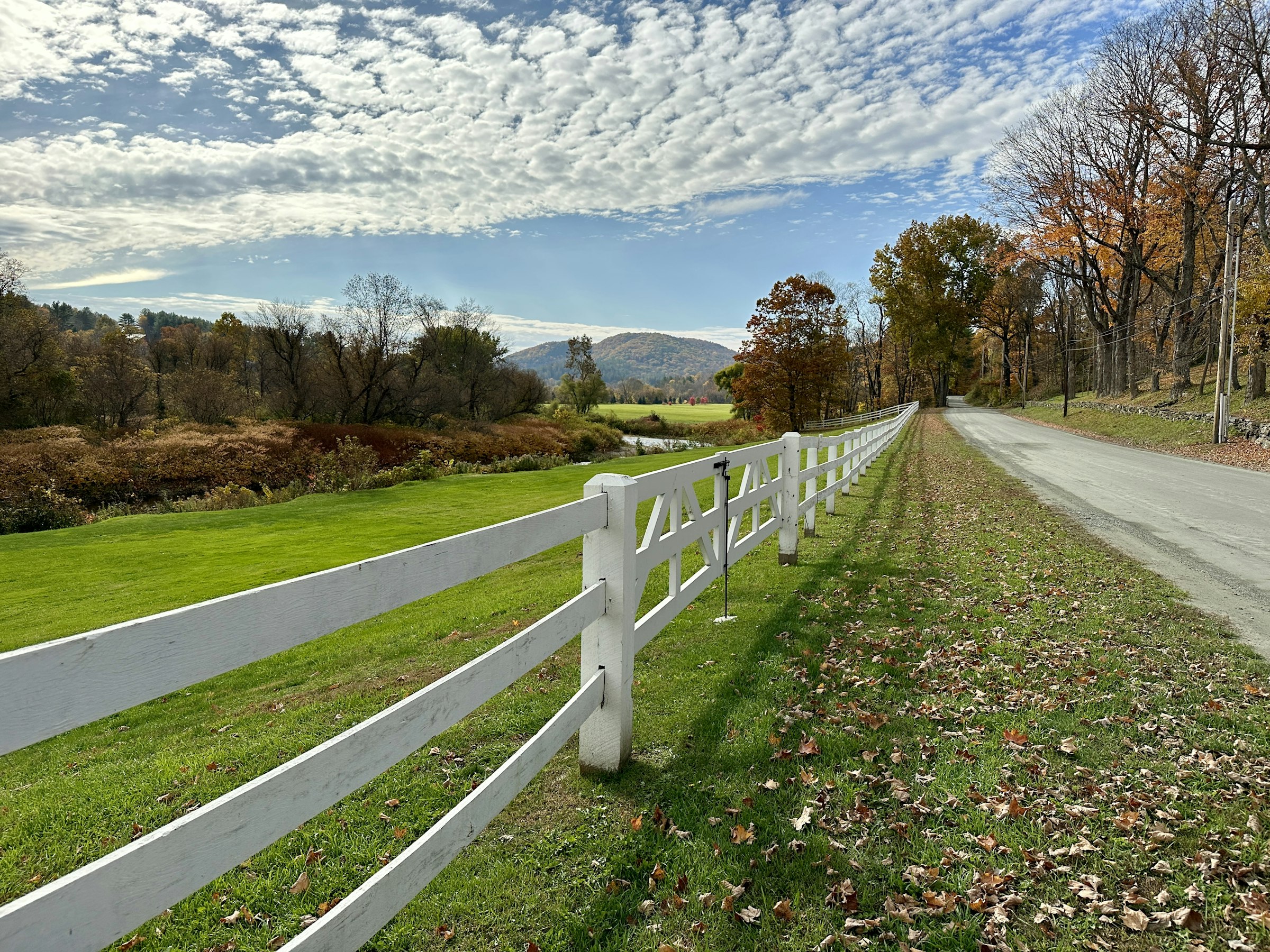 White fence along a rural road in Woodstock, Vermont. Unsplash photo location-tagged Woodstock.