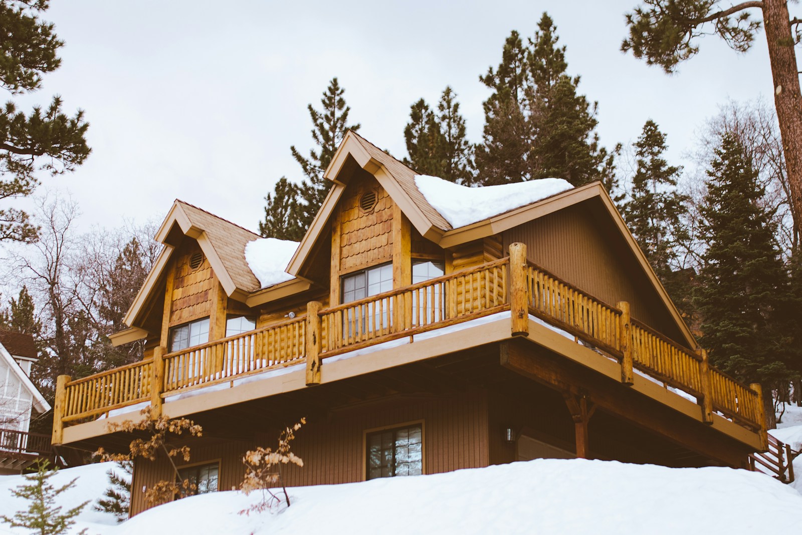 Snow-covered log cabin with wraparound deck, no people