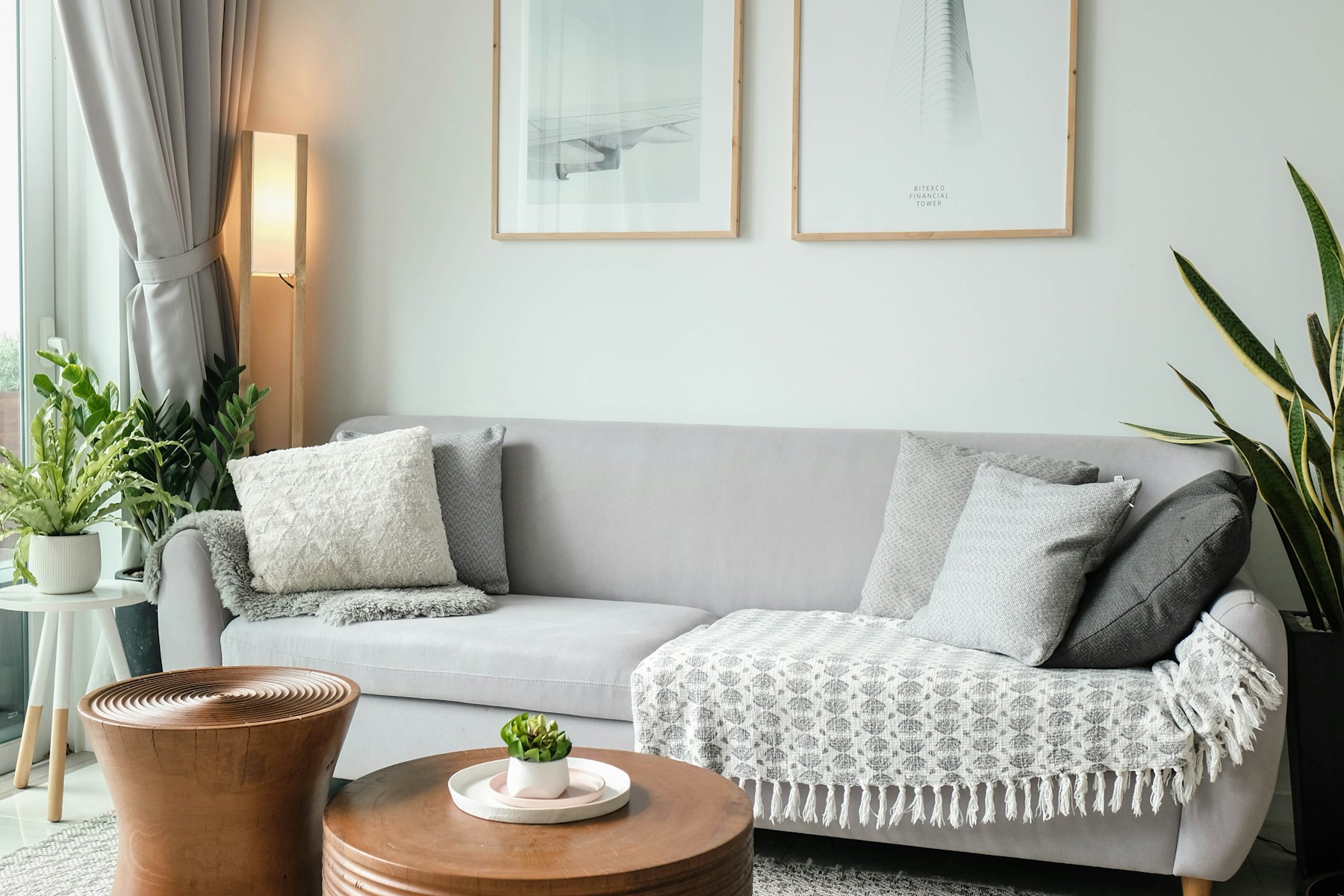 Gray rental sofa with a round wood table and a snake plant