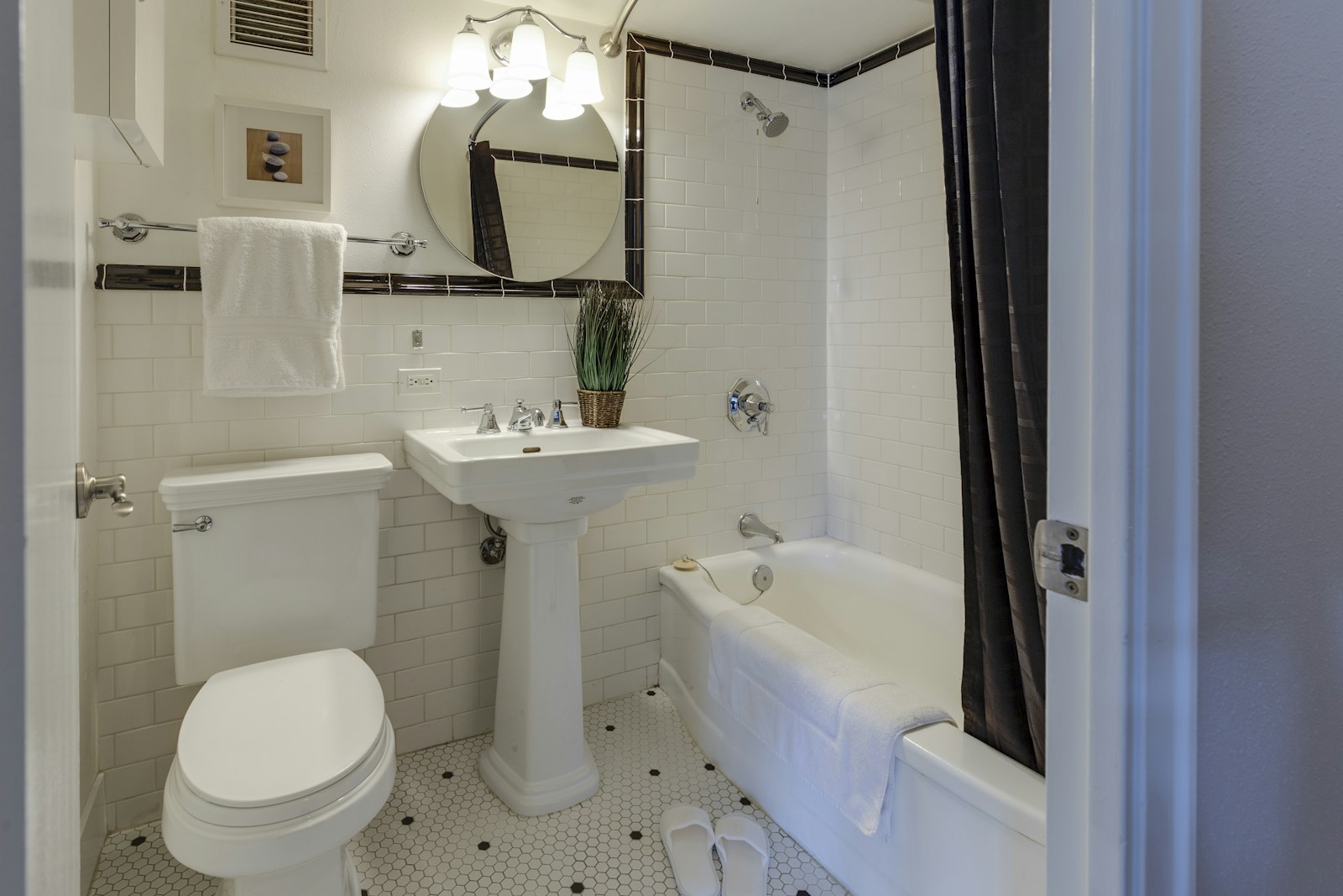 White tiled bathroom with pedestal sink and tub, no people