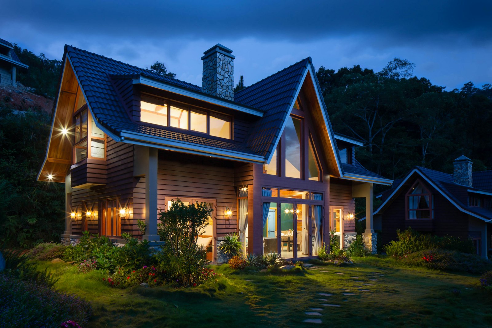 Wood cabin exterior at dusk with warm interior light and a stone path
