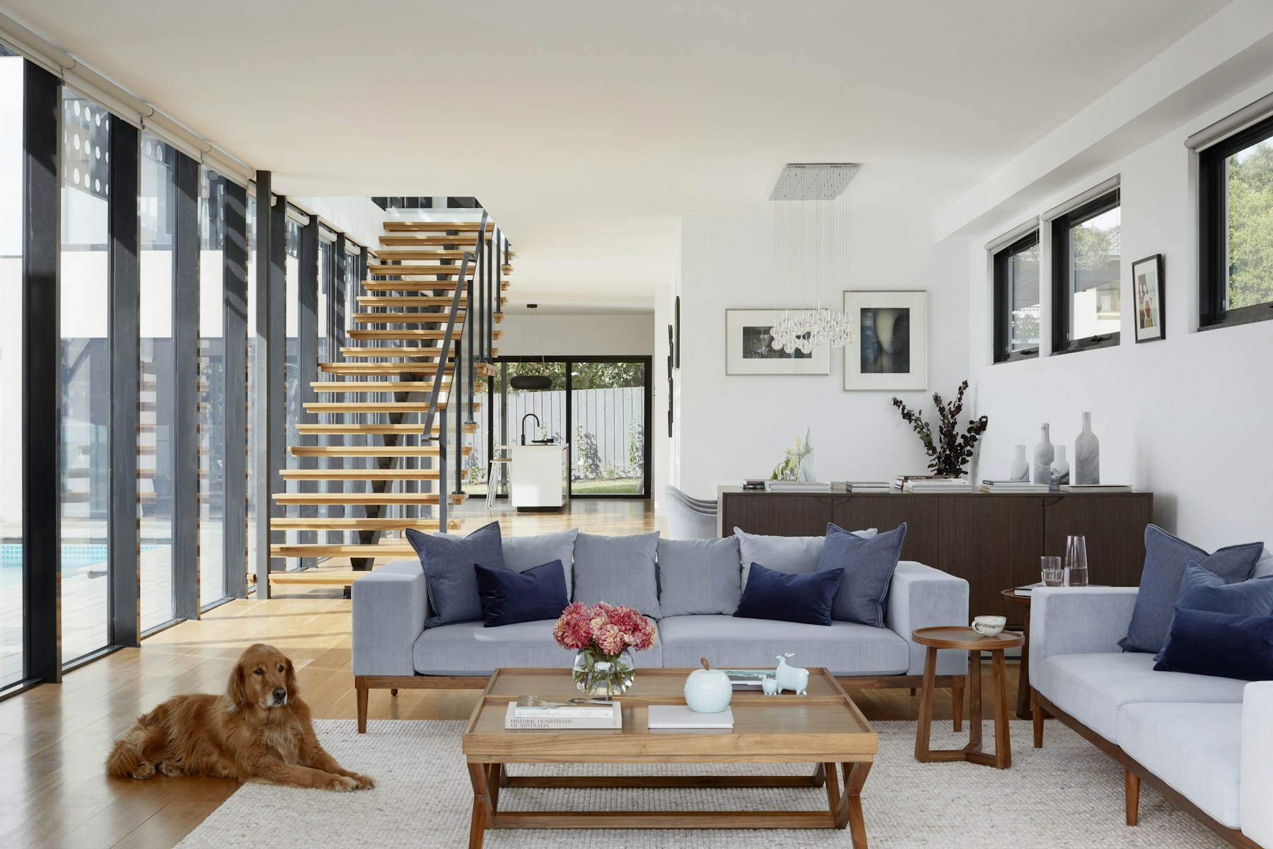 Rental living room with a gray sofa, wood stair, and glass wall