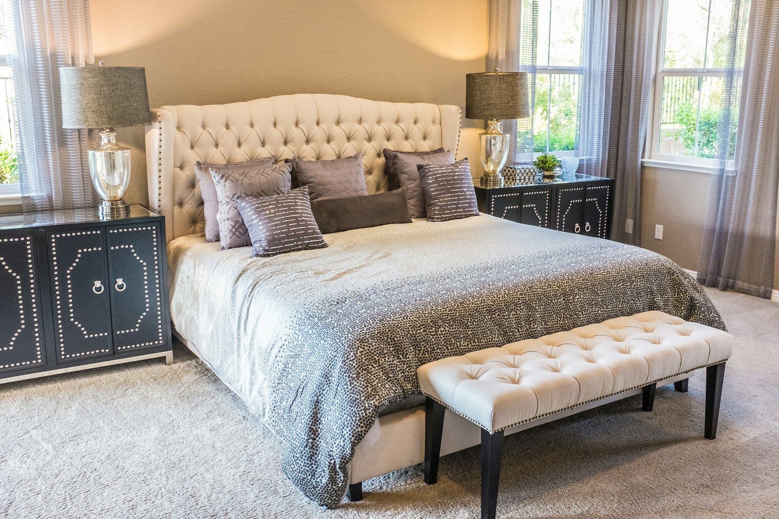 Bedroom with a tufted headboard, gray pillows, and a matching bench