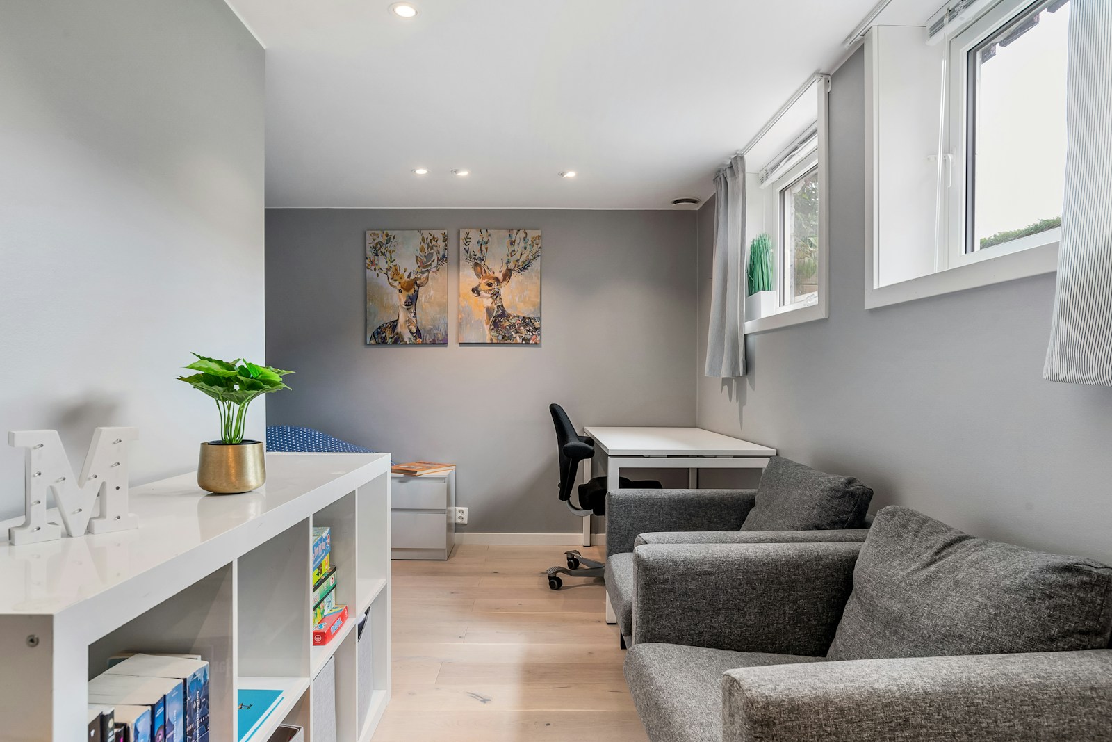 Gray sofa, desk, and deer prints in a small living room, no people