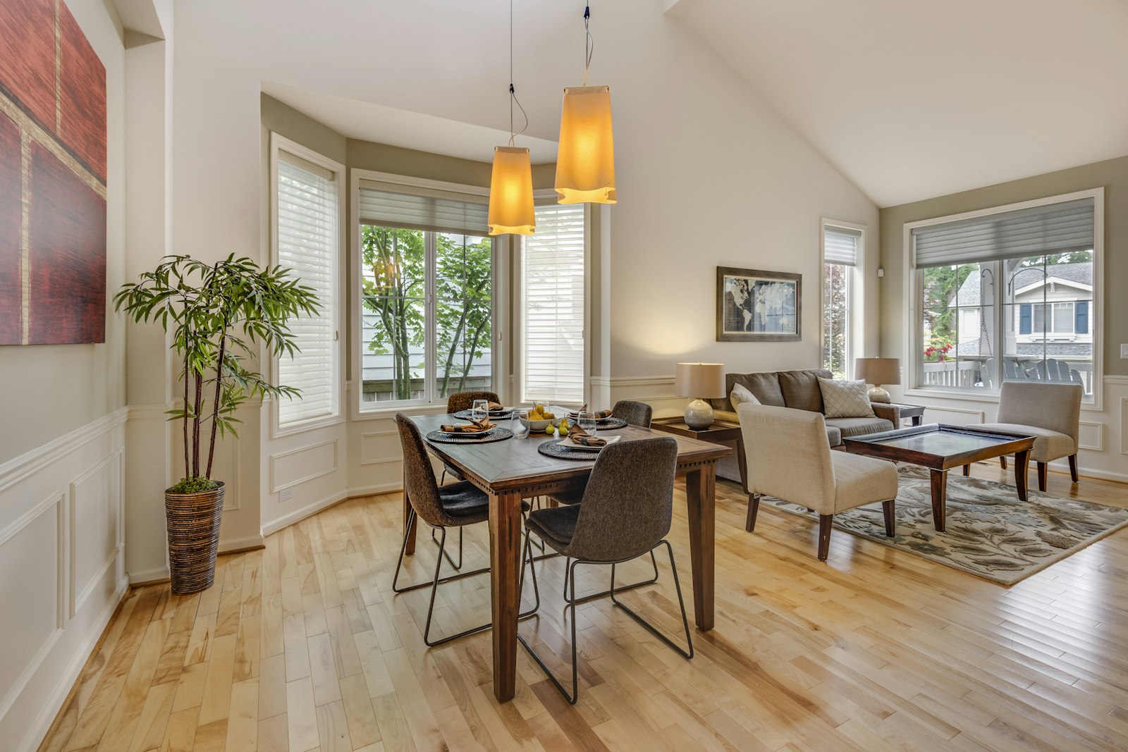 Vaulted dining and living room with a wood table and two pendant lights