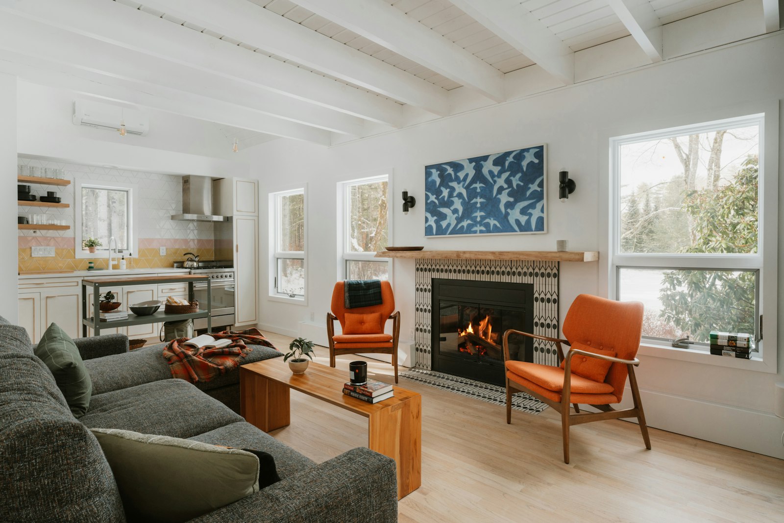 Cabin rental living room and kitchen with a fireplace and orange chairs