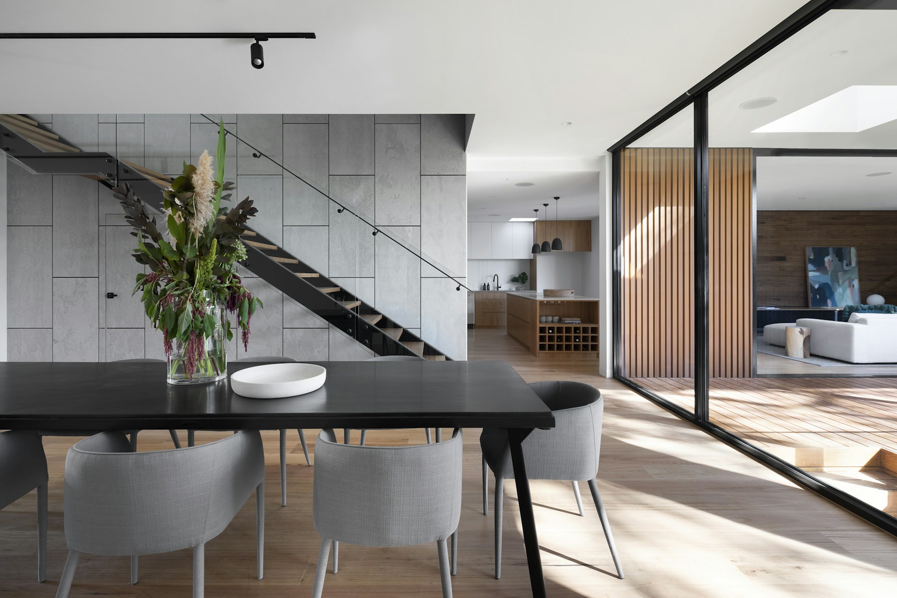 Dining room of a rental opening to a kitchen and a glass stair