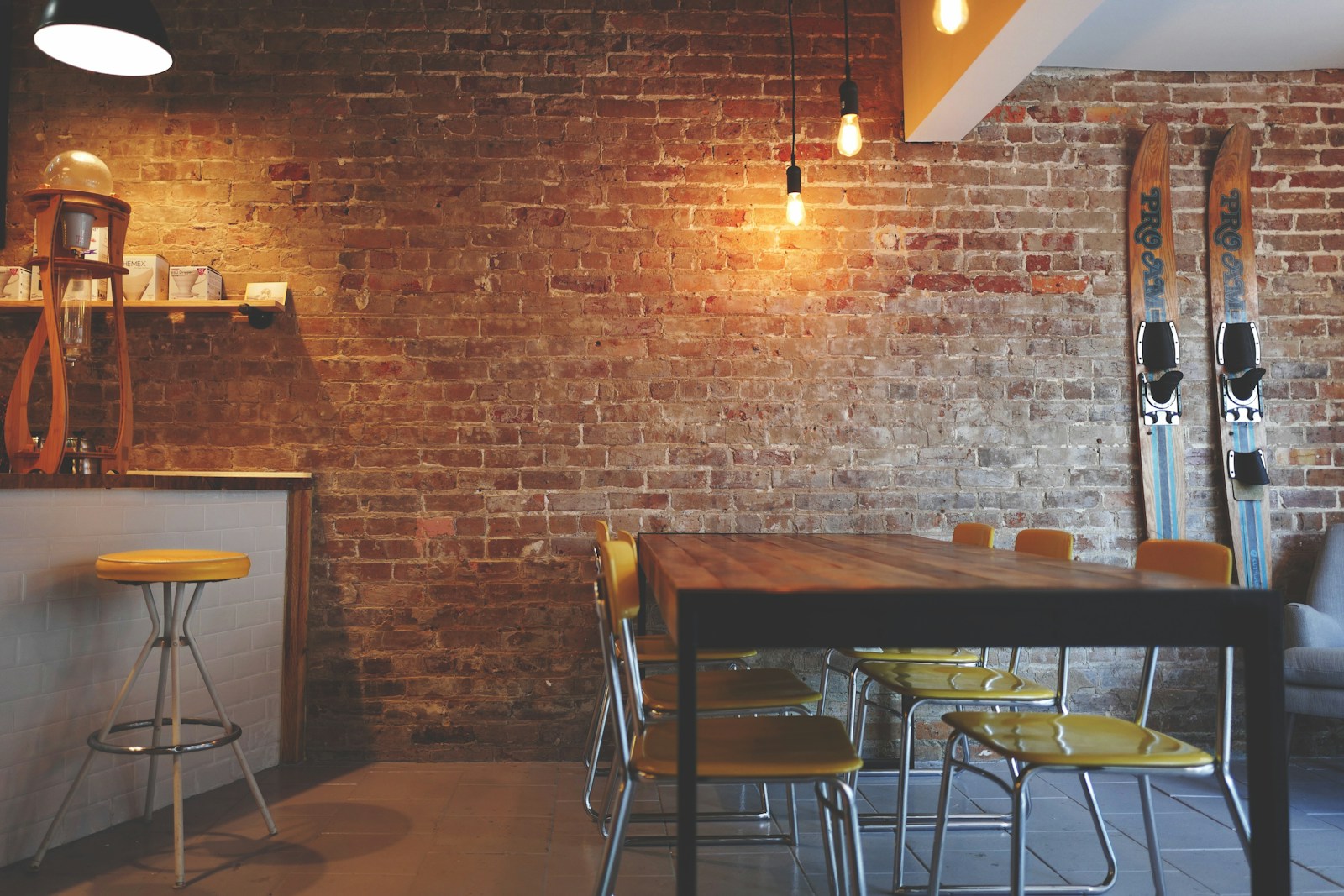 Brick dining room with long table and yellow chairs, no people