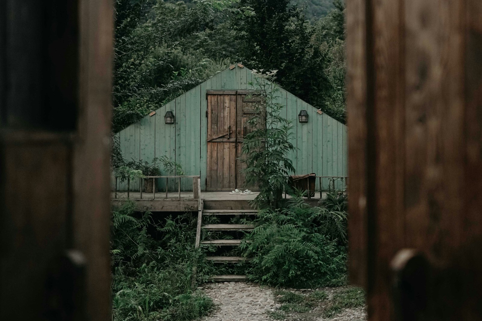 Green cabin porch seen through a doorway, no people