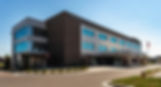 Modern Johnson County Rehabilitation Hospital building exterior with blue windows, entrance canopy, and American flag on a sunny day