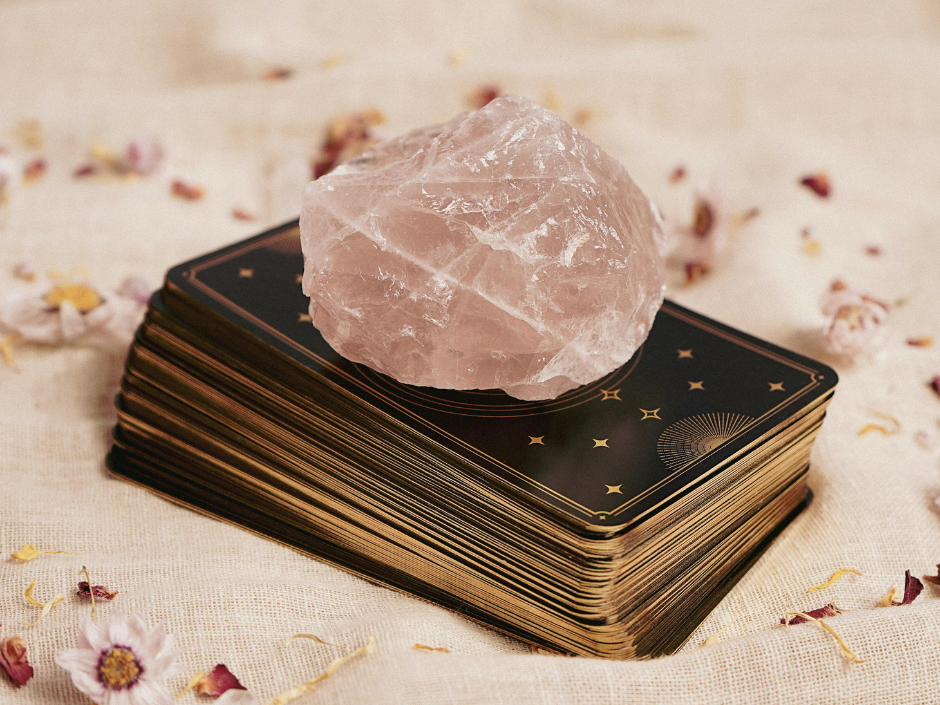 Rose quartz crystal placed on top of a tarot deck to cleanse and recharge its energy.