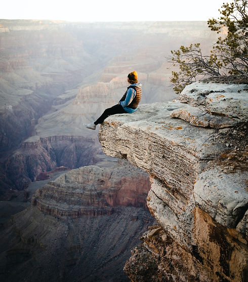 person sitting on cliff reflecting on life