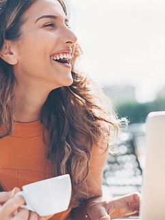 une femme avec un café et son ordinateur portable