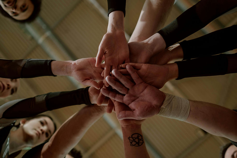 "Group of happy people in a huddle, stacking their hands together in unity and support."