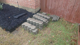 A pile of pavers around a garden bed