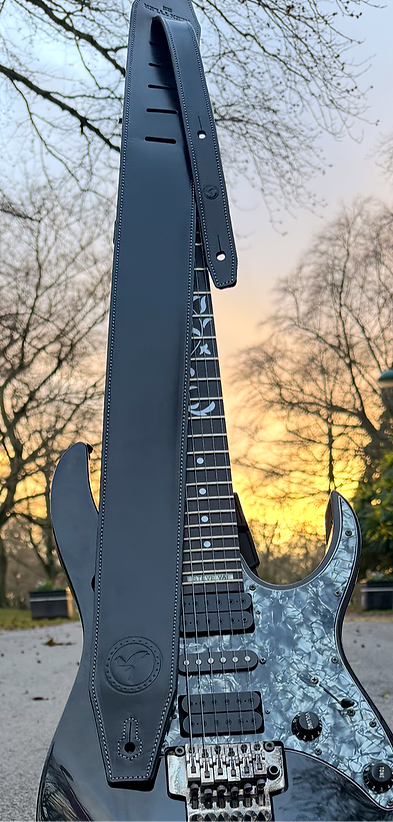 black handmade premium leather guitar strap draped over a black Steve Val electric guitar