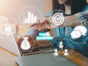 Hands point at a laptop with digital marketing icons, including charts and target. Text reads "DIGITAL MARKETING." Modern office setting.