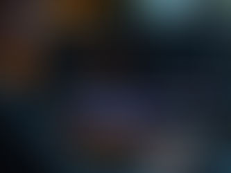 Person editing video on a computer with colorful timelines. Dark room with ambient lighting; speaker nearby. Focused and professional mood.